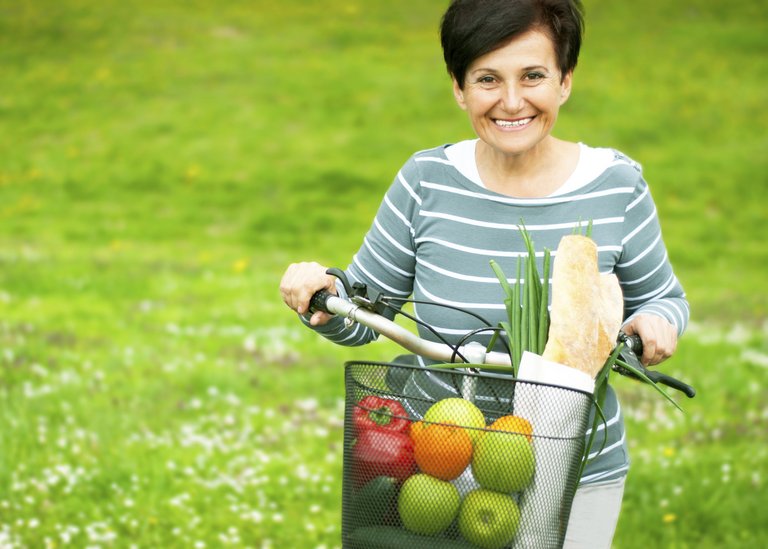 [Translate to Romania:] Woman on a bike with healthy food in the basket
