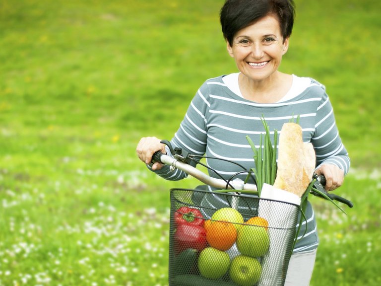 Woman on a bike with healthy food in the basket