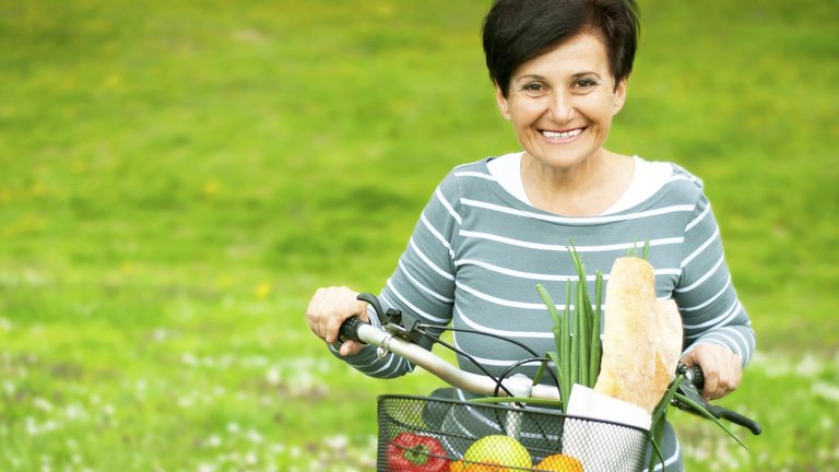 Woman on a bike with healthy food in the basket